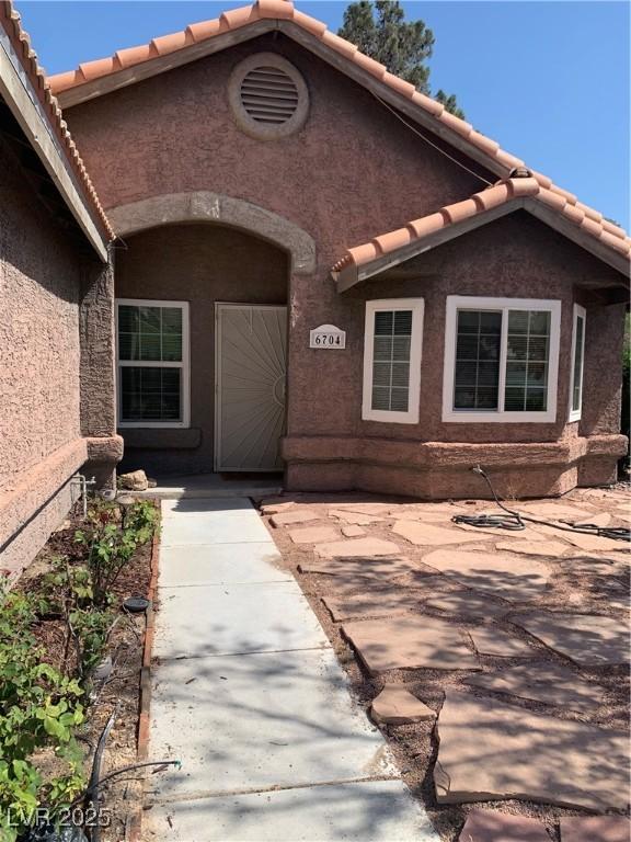 6704 Lost River Ct, Las Vegas, NV 89108 - property entrance featuring a tile roof, stucco siding, and a patio area