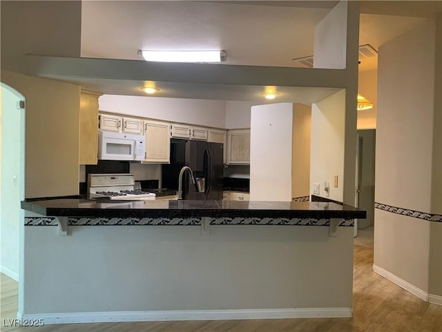 6704 Lost River Ct, Las Vegas, NV 89108 - kitchen featuring white appliances, a peninsula, light wood-type flooring, and a kitchen bar