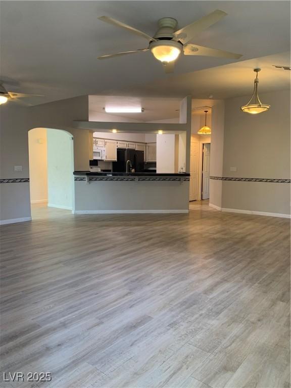 6704 Lost River Ct, Las Vegas, NV 89108 - unfurnished living room with ceiling fan, wood finished floors, and arched walkways
