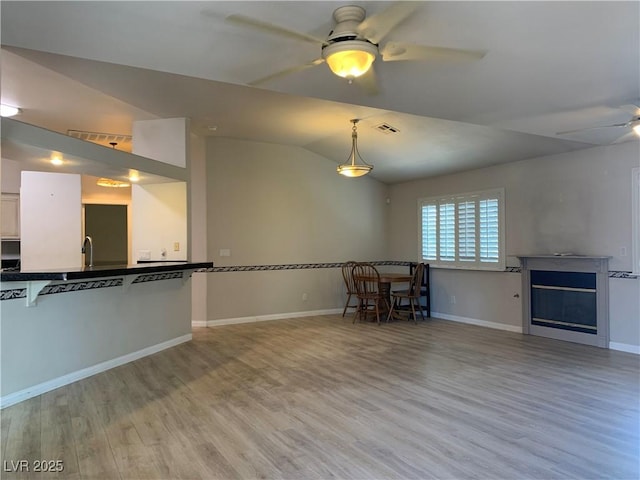 6704 Lost River Ct, Las Vegas, NV 89108 - unfurnished living room with a ceiling fan, light wood-style flooring, a fireplace, and vaulted ceiling