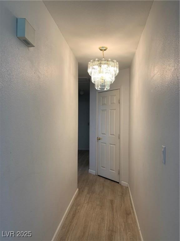 6704 Lost River Ct, Las Vegas, NV 89108 - corridor featuring light wood-style flooring and a chandelier