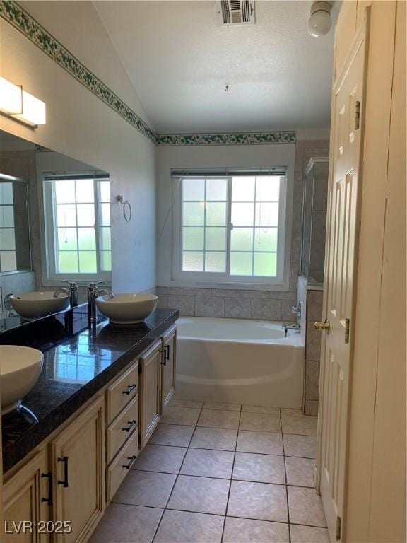 6704 Lost River Ct, Las Vegas, NV 89108 - bathroom featuring vaulted ceiling, a garden tub, double vanity, tile patterned floors, and a shower stall