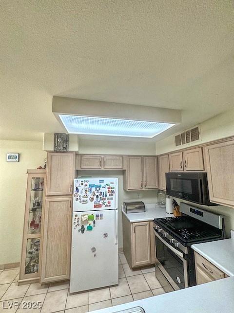 3101 Casey Dr Unit 204, Las Vegas, NV 89120 - kitchen with black microwave, freestanding refrigerator, gas stove, light tile patterned flooring, and light countertops