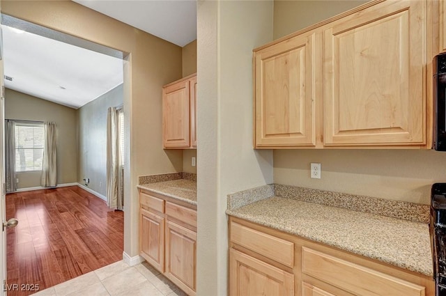 3609 Blue Pimpernel Ave, North Las Vegas, NV 89081 - kitchen featuring light brown cabinetry, vaulted ceiling, and light tile patterned floors