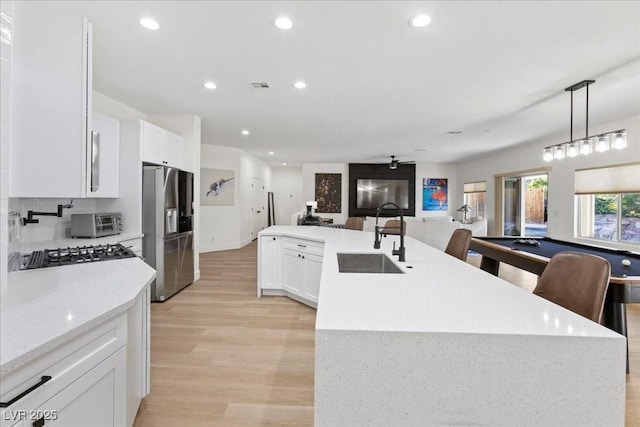 9612 Glengarry Dr, Las Vegas, NV 89129 - kitchen with appliances with stainless steel finishes, light wood-style flooring, open floor plan, white cabinetry, and hanging light fixtures