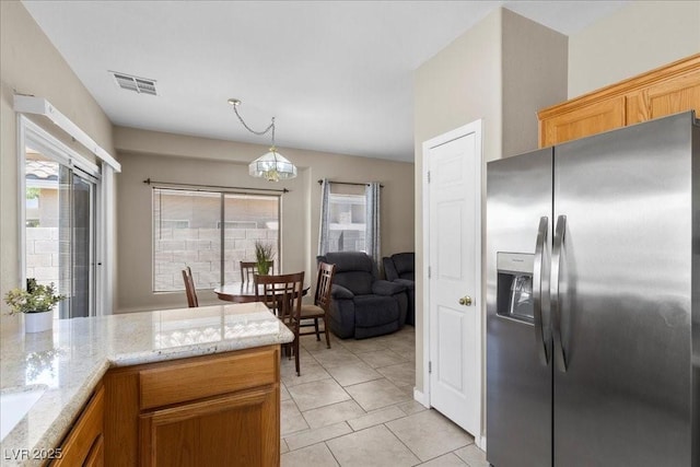8563 Red Diamond St, Las Vegas, NV 89123 - kitchen with stainless steel refrigerator with ice dispenser, light tile patterned floors, light stone counters, and decorative light fixtures