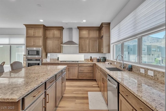 11695 Gentle Birdsong Ave, Las Vegas, NV 89138 - kitchen featuring stainless steel appliances, wall chimney range hood, light wood-style flooring, a kitchen island, and light stone countertops
