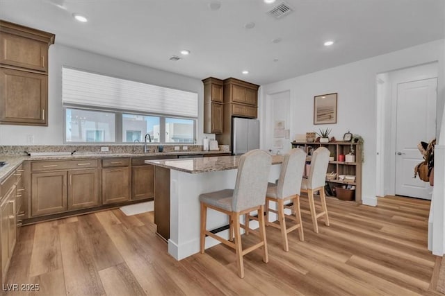11695 Gentle Birdsong Ave, Las Vegas, NV 89138 - kitchen featuring freestanding refrigerator, light wood finished floors, a breakfast bar area, a center island, and recessed lighting