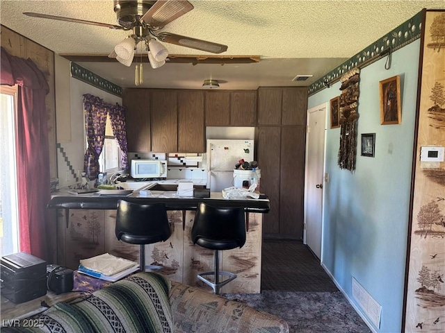 1507 Elizabeth Ave Unit 1, Las Vegas, NV 89119 - kitchen with white appliances, ceiling fan, a textured ceiling, and dark colored carpet