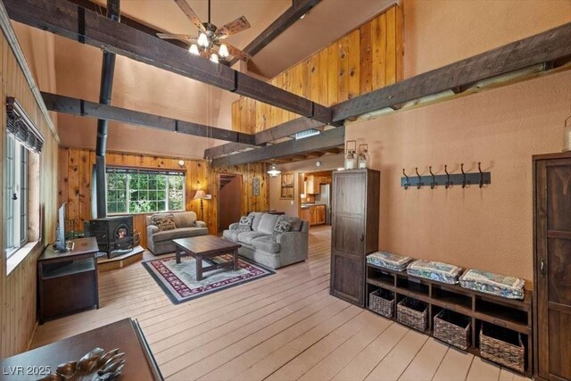 4581 Aspen Ave, Mount Charleston, NV 89124 - living area featuring a wood stove, a ceiling fan, a towering ceiling, hardwood / wood-style flooring, and wood walls