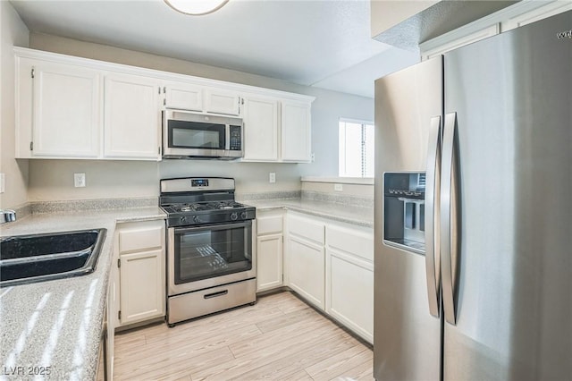 2229 Bowstring Dr, Las Vegas, NV 89142 - kitchen with appliances with stainless steel finishes, white cabinetry, light countertops, and light wood-style flooring