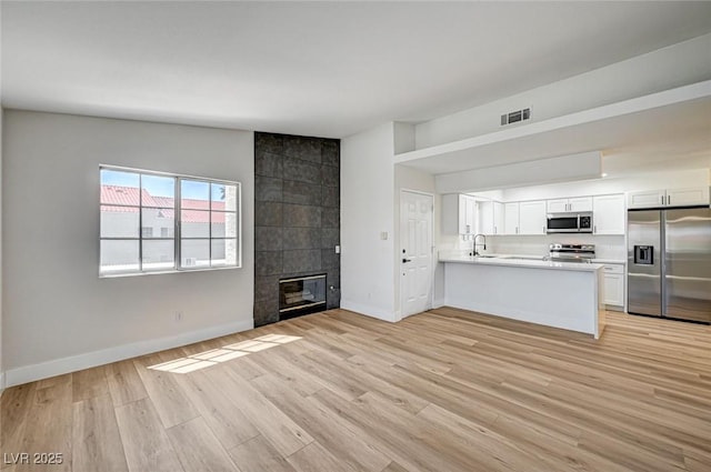 2725 S Nellis Blvd Unit 2036, Las Vegas, NV 89121 - unfurnished living room with light wood-style floors and a tiled fireplace