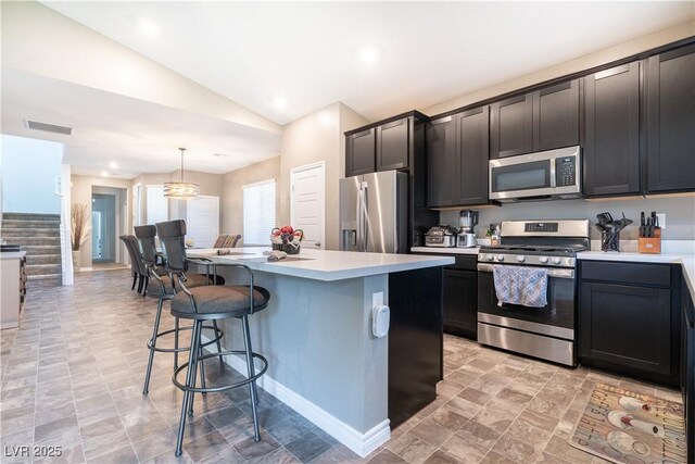 4376 Latitude Valley Ct, North Las Vegas, NV 89084 - kitchen featuring appliances with stainless steel finishes, vaulted ceiling, a kitchen breakfast bar, a center island, and light countertops