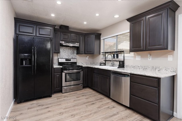 317 Brent Ct, Henderson, NV 89074 - kitchen with appliances with stainless steel finishes, under cabinet range hood, recessed lighting, light wood-style flooring, and light stone counters