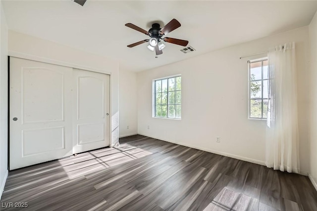 10428 Mulvaney Cir, Las Vegas, NV 89141 - unfurnished bedroom with multiple windows, dark wood-style floors, a closet, and a ceiling fan
