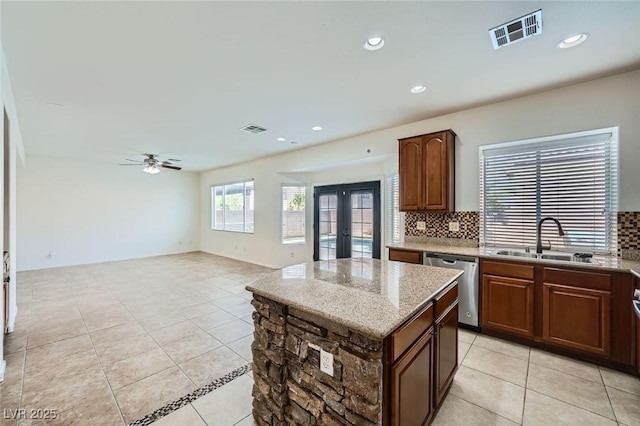 10428 Mulvaney Cir, Las Vegas, NV 89141 - kitchen with dishwasher, ceiling fan, tasteful backsplash, light stone counters, and light tile patterned floors