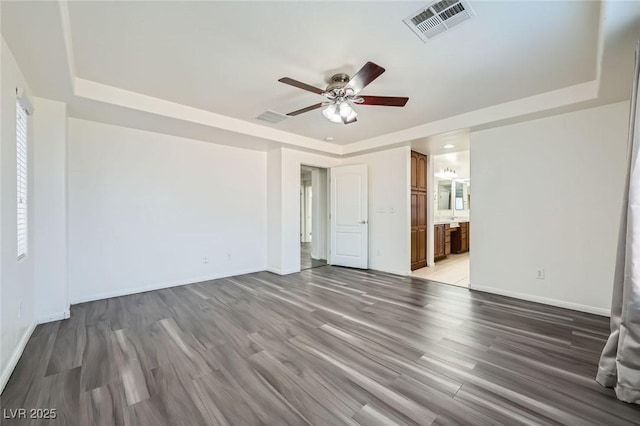 10428 Mulvaney Cir, Las Vegas, NV 89141 - unfurnished bedroom featuring a tray ceiling, light wood-type flooring, ensuite bath, and ceiling fan