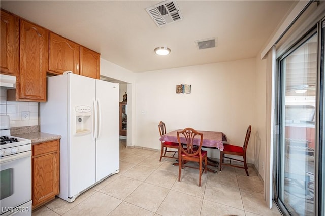 4616 E Idaho Ave, Las Vegas, NV 89104 - kitchen featuring white appliances, brown cabinets, under cabinet range hood, and backsplash