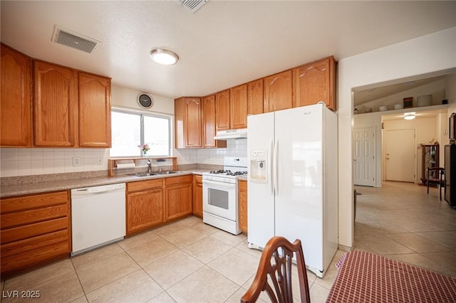 4616 E Idaho Ave, Las Vegas, NV 89104 - kitchen featuring white appliances, under cabinet range hood, light tile patterned floors, backsplash, and brown cabinetry
