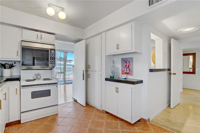 205 E Harmon Ave Unit 306, Las Vegas, NV 89169 - kitchen with stainless steel microwave, electric range, light tile patterned floors, white cabinetry, and dark countertops