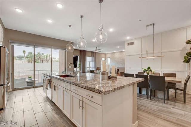 4336 Guava Ct Unit 0, Las Vegas, NV 89135 - kitchen with a ceiling fan, white cabinets, an island with sink, light stone countertops, and hanging light fixtures