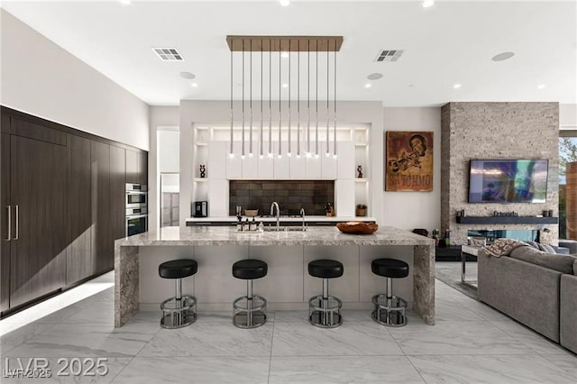 387 Solitude Peak Ln, Henderson, NV 89012 - kitchen with modern cabinets, a breakfast bar, light marble finish flooring, open floor plan, and recessed lighting