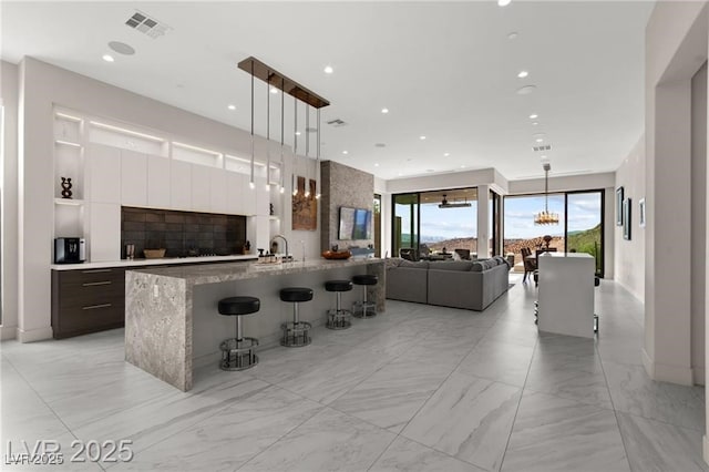 387 Solitude Peak Ln, Henderson, NV 89012 - kitchen with modern cabinets, a kitchen breakfast bar, white cabinetry, light marble finish flooring, and pendant lighting