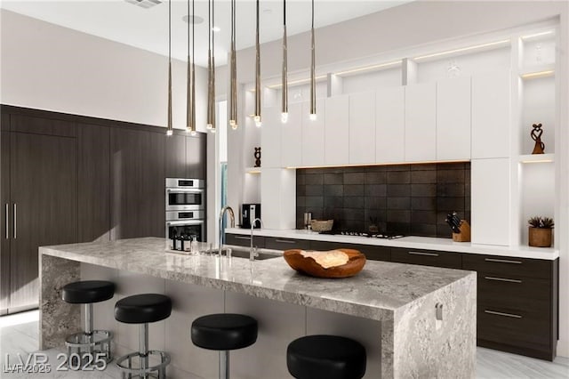 387 Solitude Peak Ln, Henderson, NV 89012 - kitchen featuring dark brown cabinets, a breakfast bar, double oven, and modern cabinets