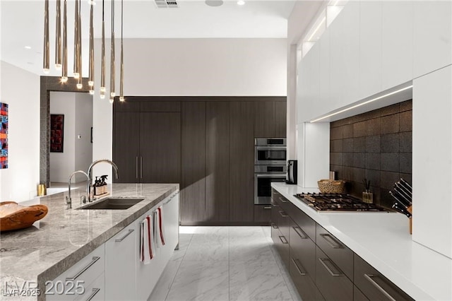 387 Solitude Peak Ln, Henderson, NV 89012 - kitchen featuring modern cabinets, appliances with stainless steel finishes, light marble finish flooring, decorative light fixtures, and white cabinetry