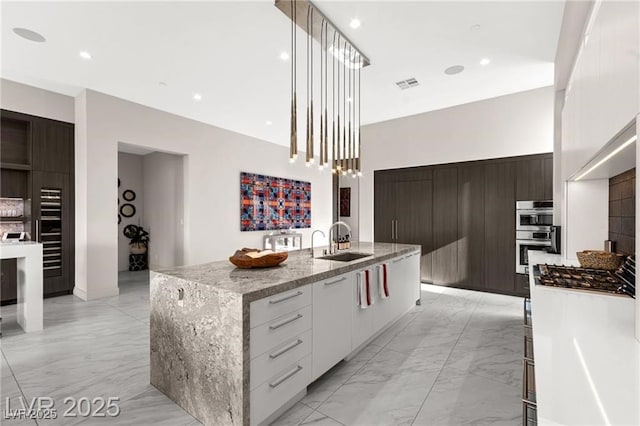 387 Solitude Peak Ln, Henderson, NV 89012 - kitchen with modern cabinets, light marble finish flooring, stainless steel appliances, a large island, and recessed lighting