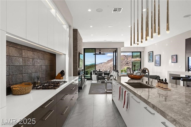 387 Solitude Peak Ln, Henderson, NV 89012 - kitchen featuring modern cabinets, stainless steel gas stovetop, white cabinetry, decorative light fixtures, and light stone counters