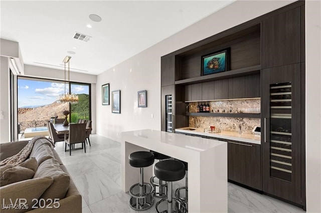 387 Solitude Peak Ln, Henderson, NV 89012 - indoor bar featuring light marble finish flooring, a chandelier, decorative backsplash, wine cooler, and pendant lighting