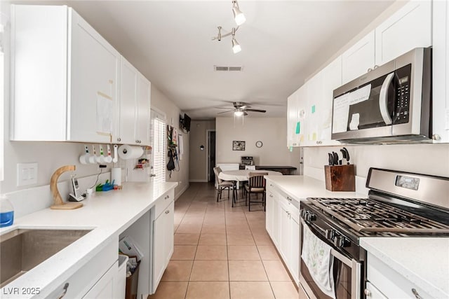 4168 Wendy Ln, Las Vegas, NV 89115 - kitchen with stainless steel appliances, light tile patterned floors, and white cabinetry