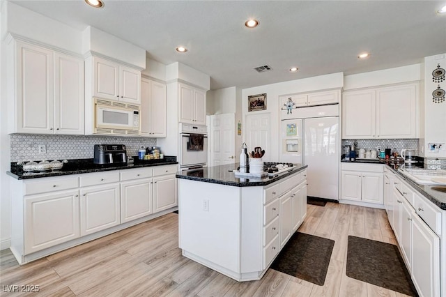 2496 Ram Crossing Way, Henderson, NV 89074 - kitchen featuring built in appliances, a kitchen island, backsplash, white cabinetry, and light wood-style floors