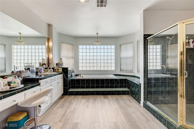 2496 Ram Crossing Way, Henderson, NV 89074 - full bathroom with vanity, a bath, a shower stall, wood finished floors, and a chandelier