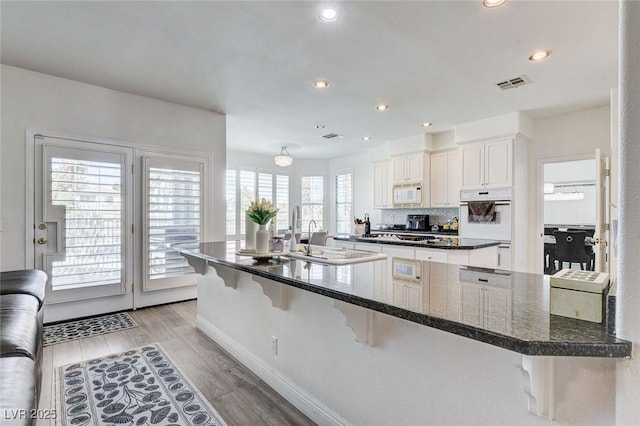 2496 Ram Crossing Way, Henderson, NV 89074 - kitchen with white microwave, a kitchen bar, light wood-style floors, a kitchen island, and recessed lighting