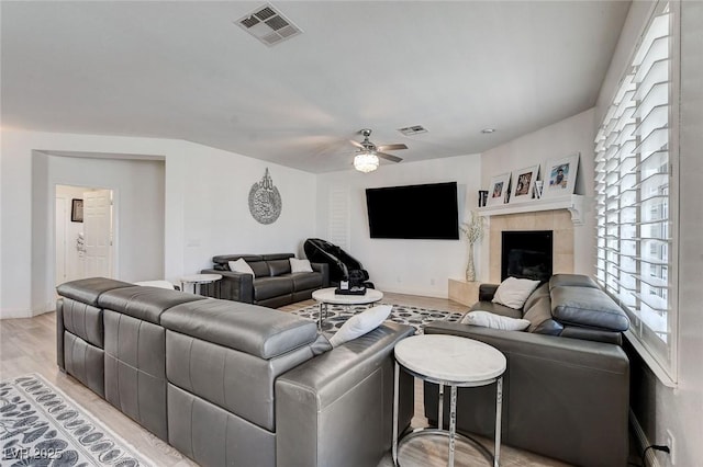 2496 Ram Crossing Way, Henderson, NV 89074 - living room with light wood-style flooring, ceiling fan, healthy amount of natural light, and a tiled fireplace
