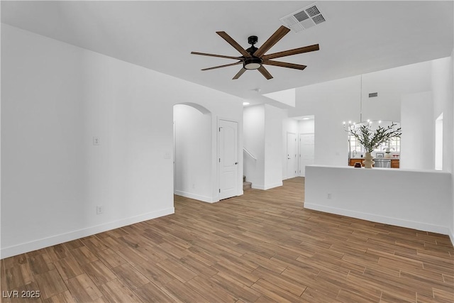 9047 Harbor Wind Ave, Las Vegas, NV 89178 - unfurnished living room featuring ceiling fan, arched walkways, a chandelier, and wood finished floors