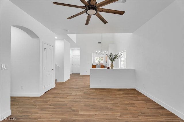 9047 Harbor Wind Ave, Las Vegas, NV 89178 - unfurnished room featuring a ceiling fan, a chandelier, arched walkways, and wood finished floors