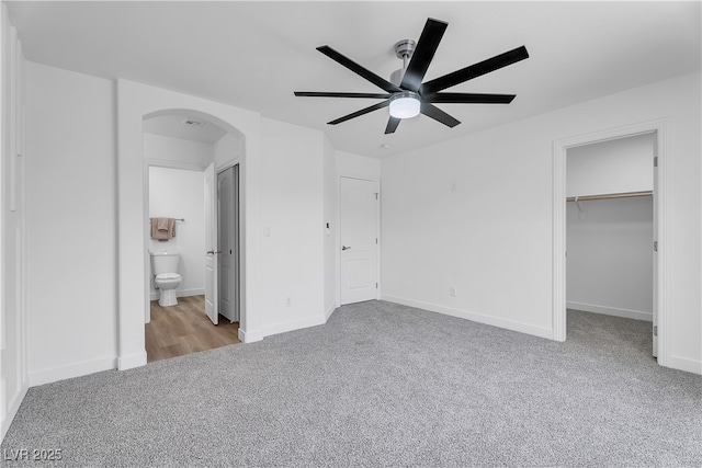 9047 Harbor Wind Ave, Las Vegas, NV 89178 - unfurnished bedroom featuring arched walkways, carpet, a walk in closet, ceiling fan, and ensuite bathroom