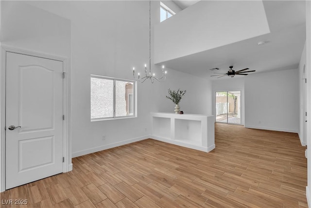 9047 Harbor Wind Ave, Las Vegas, NV 89178 - empty room with a towering ceiling, a chandelier, light wood finished floors, and a ceiling fan