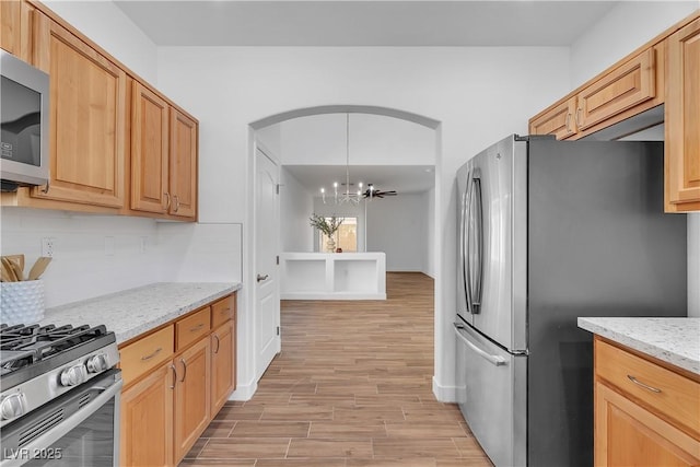 9047 Harbor Wind Ave, Las Vegas, NV 89178 - kitchen with stainless steel appliances, a chandelier, light wood-type flooring, decorative backsplash, and light stone counters
