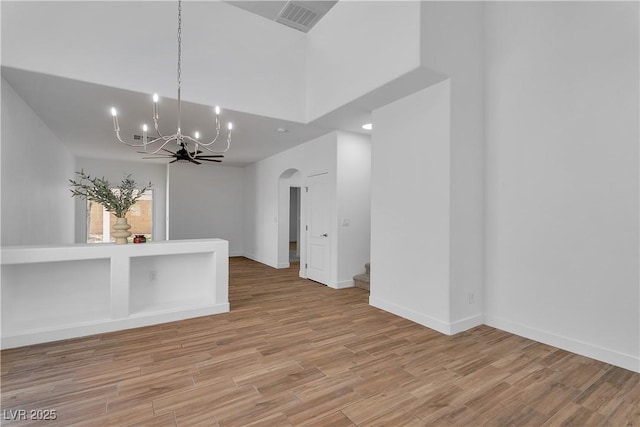 9047 Harbor Wind Ave, Las Vegas, NV 89178 - unfurnished room featuring arched walkways, a chandelier, stairs, and light wood-style flooring