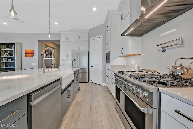 112 Springbough Ln, Las Vegas, NV 89138 - kitchen with appliances with stainless steel finishes, wall chimney exhaust hood, white cabinets, pendant lighting, and light wood-type flooring