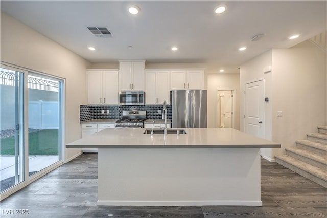 545 Thea St Unit 1315, Henderson, NV 89052 - kitchen with stainless steel appliances, dark wood-type flooring, an island with sink, white cabinetry, and backsplash