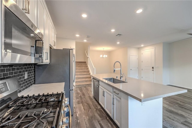 545 Thea St Unit 1315, Henderson, NV 89052 - kitchen with appliances with stainless steel finishes, dark wood-type flooring, an island with sink, a chandelier, and decorative backsplash