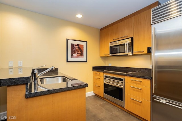 2000 Fashion Show Dr Unit 5022, Las Vegas, NV 89109 - kitchen with appliances with stainless steel finishes, dark tile patterned floors, brown cabinetry, dark stone countertops, and recessed lighting
