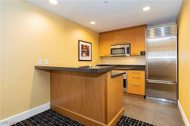 2000 Fashion Show Dr Unit 5022, Las Vegas, NV 89109 - kitchen featuring stainless steel appliances, a peninsula, dark countertops, a kitchen breakfast bar, and recessed lighting
