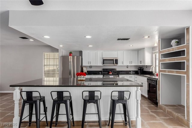 5905 Paseo Montana, Las Vegas, NV 89108 - kitchen featuring appliances with stainless steel finishes, white cabinetry, a kitchen bar, dark countertops, and recessed lighting
