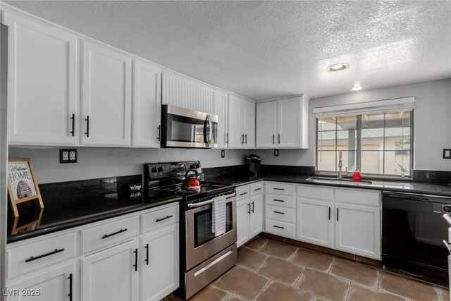 5905 Paseo Montana, Las Vegas, NV 89108 - kitchen with appliances with stainless steel finishes, a textured ceiling, white cabinets, dark countertops, and dark tile patterned floors